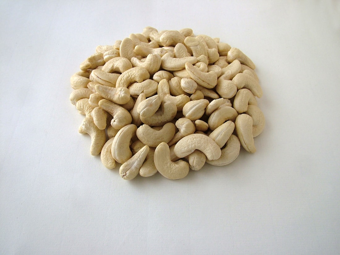 Amandes de cajou décortiquées blanches sur une surface claire